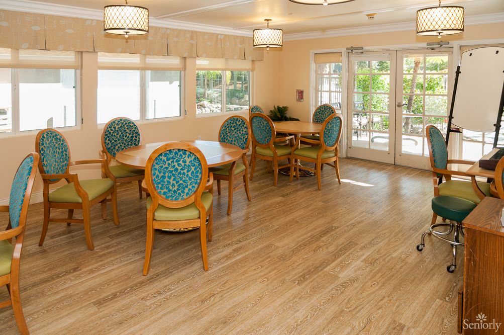 A bright and inviting dining area with wooden flooring, round tables, and cushioned chairs.