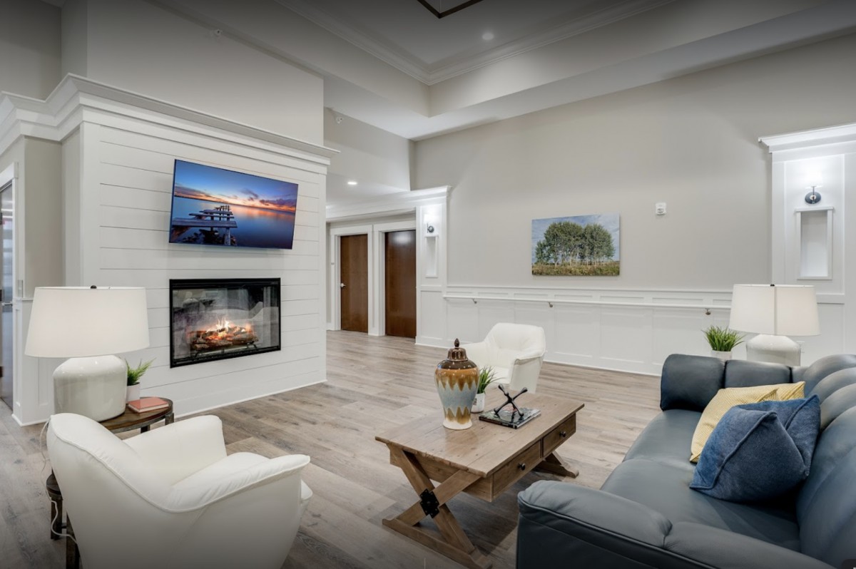 A modern living room featuring a fireplace and television, with elegant seating and artwork adorning the walls.