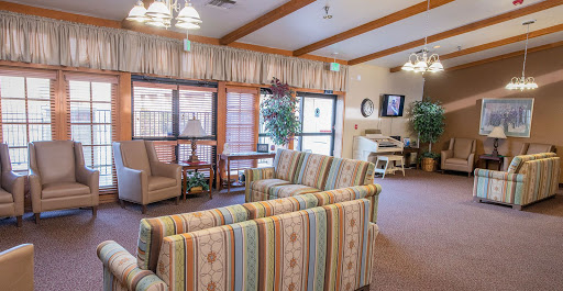 A cozy living room area featuring striped couches and comfortable chairs, with natural light streaming through the windows.