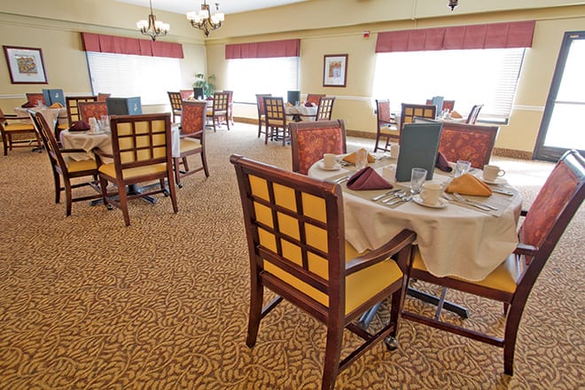 A neatly arranged dining room with tables set for a meal.