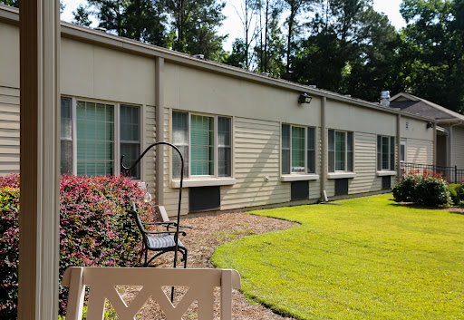 A view of a modern building exterior with multiple windows, surrounded by well-maintained grass and garden.