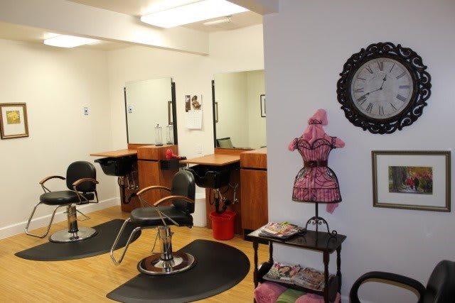 A cozy hair salon with styling stations, mirrors, and a waiting area adorned with a decorative mannequin and clock.