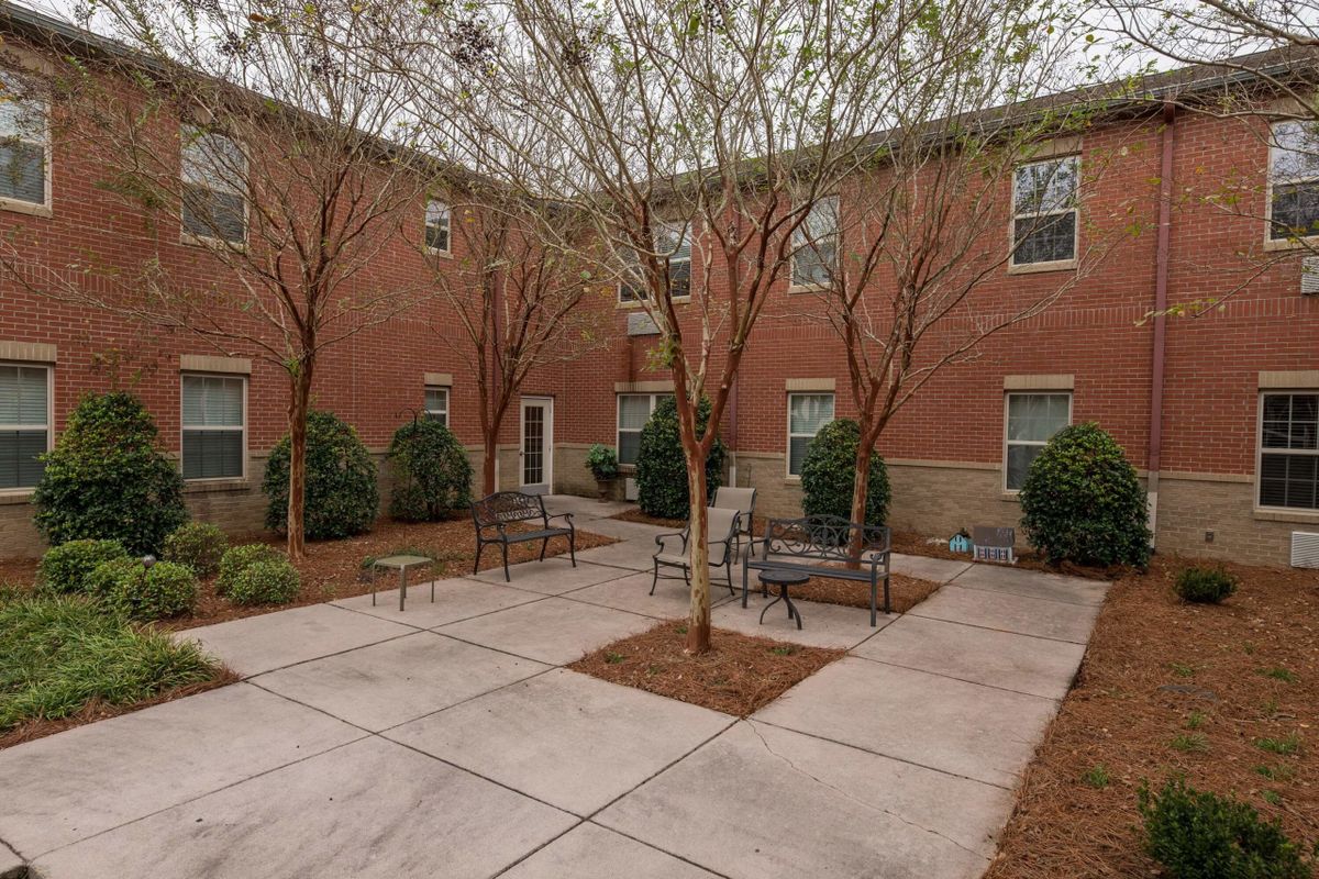 A quiet courtyard featuring benches and trees surrounded by a brick building.