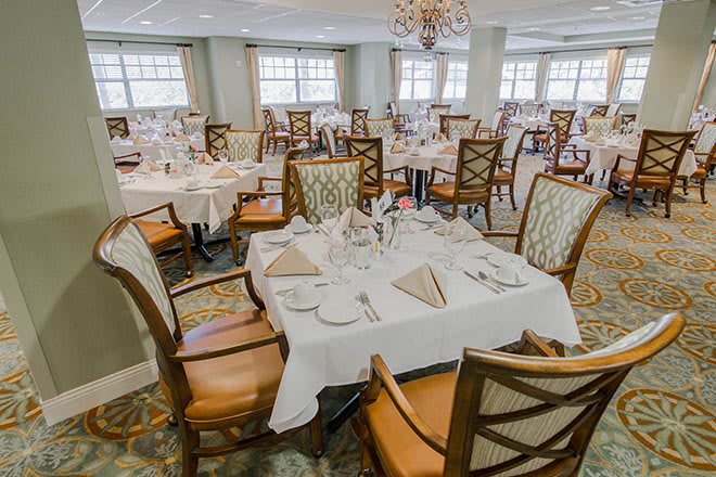 An elegant dining room setup with neatly arranged tables and chairs, prepared for guests.