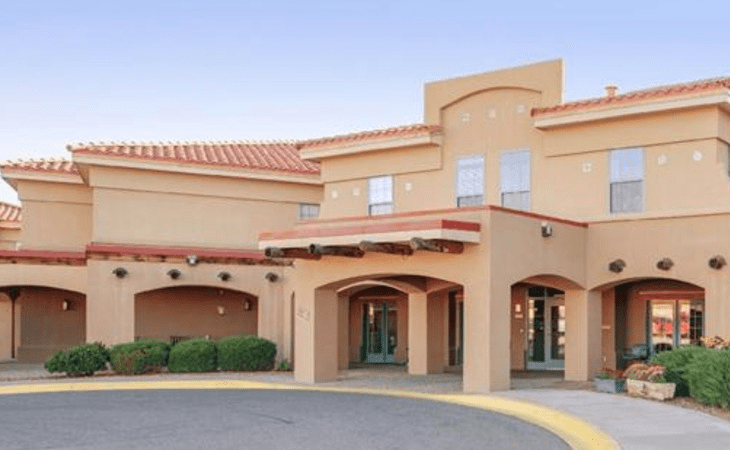 The image shows the exterior of a hotel with a prominent entrance.