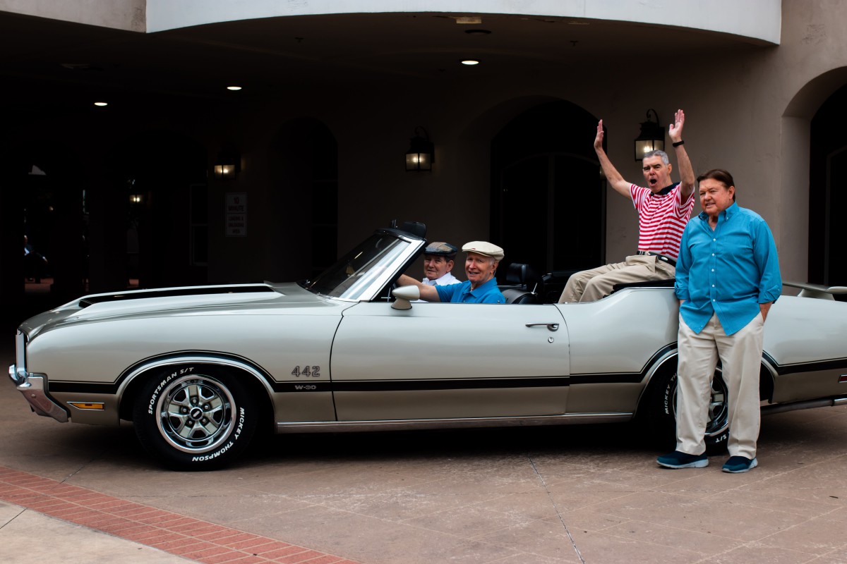 A group of people enjoying a ride in a vintage convertible car.