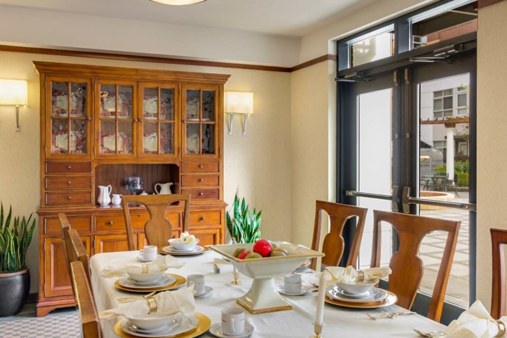 A well-appointed dining room featuring a set dining table with elegant tableware and a classic china cabinet in the background.
