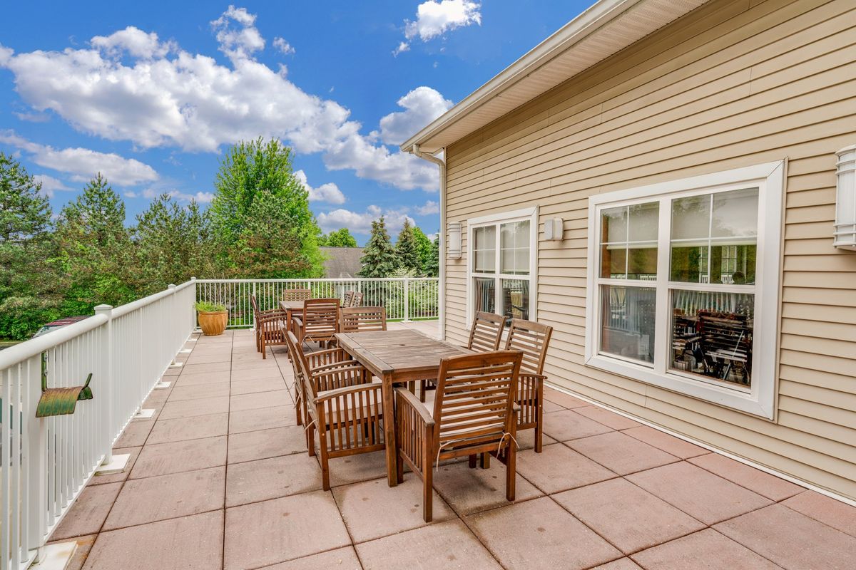 A spacious outdoor patio with wooden furniture under a bright blue sky.