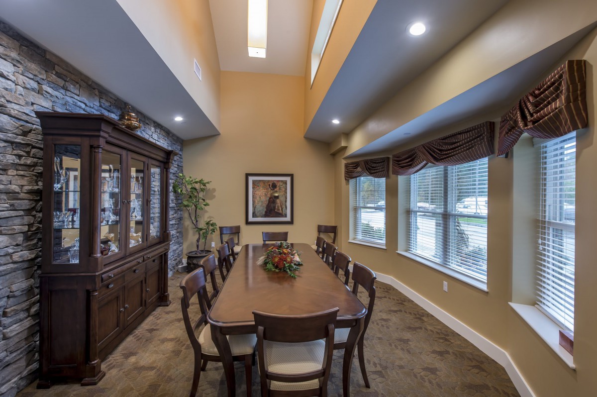 Elegant dining room with a long table, chairs, and large windows.