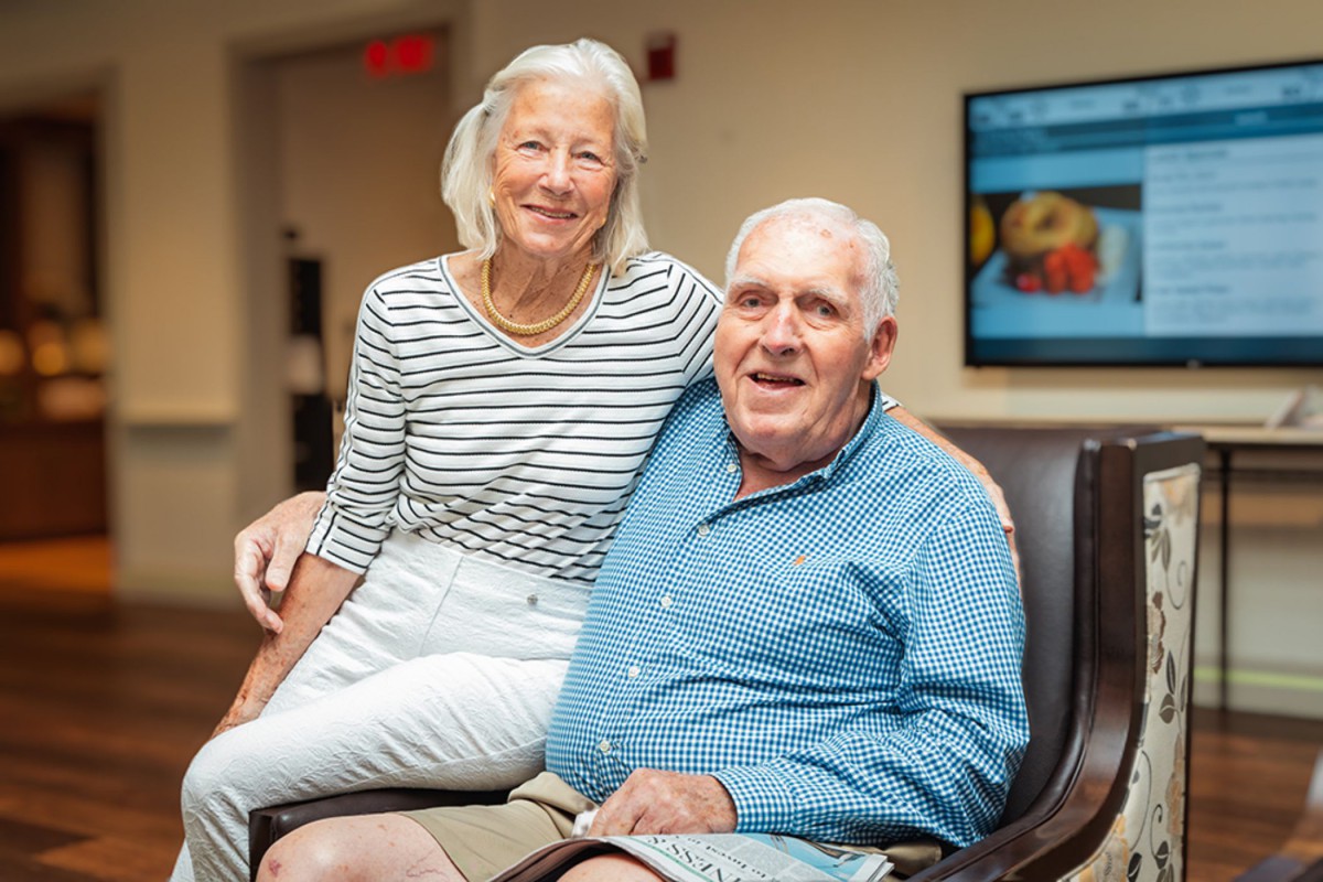 An elderly couple smiling while seated indoors.