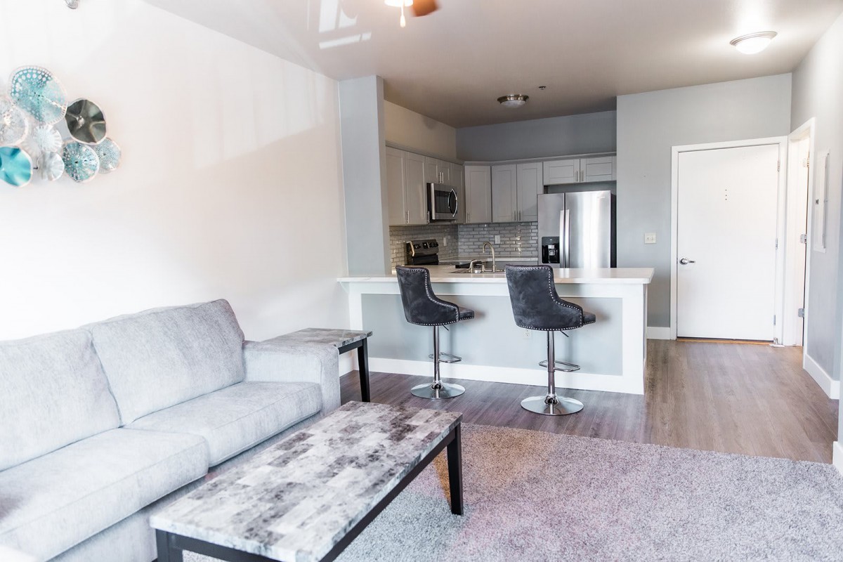 A modern apartment with an open layout featuring a living room and kitchen area.