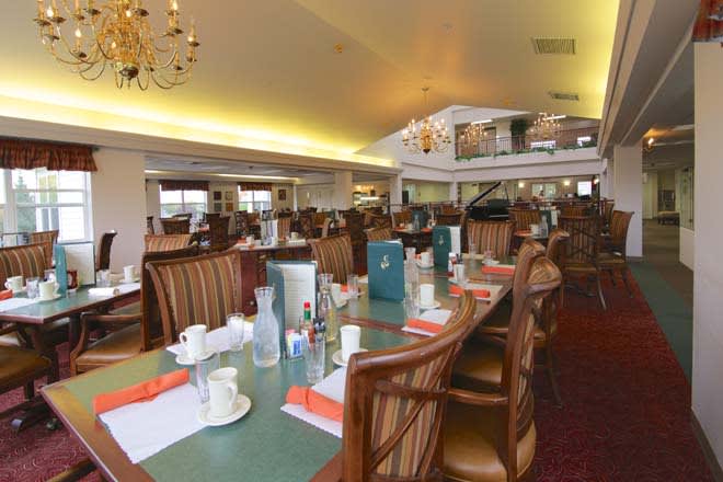 A spacious restaurant dining area with elegantly arranged tables and chandeliers.