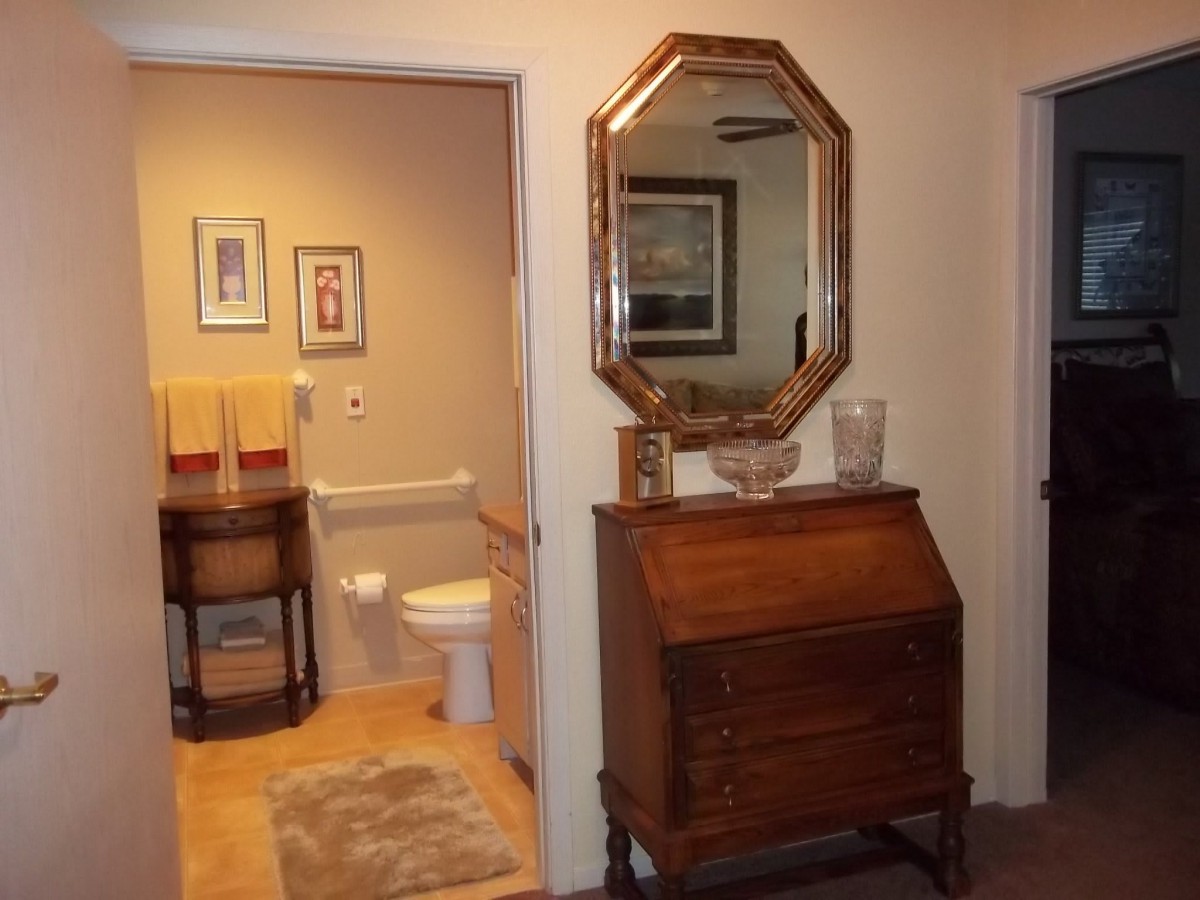 A cozy interior view featuring a bathroom with wall art, a wooden cabinet with an octagonal mirror above, and decorative elements.