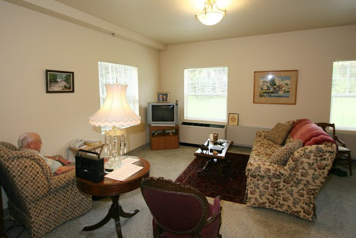 A cozy living room featuring a floral sofa, a vintage lamp, and a television.