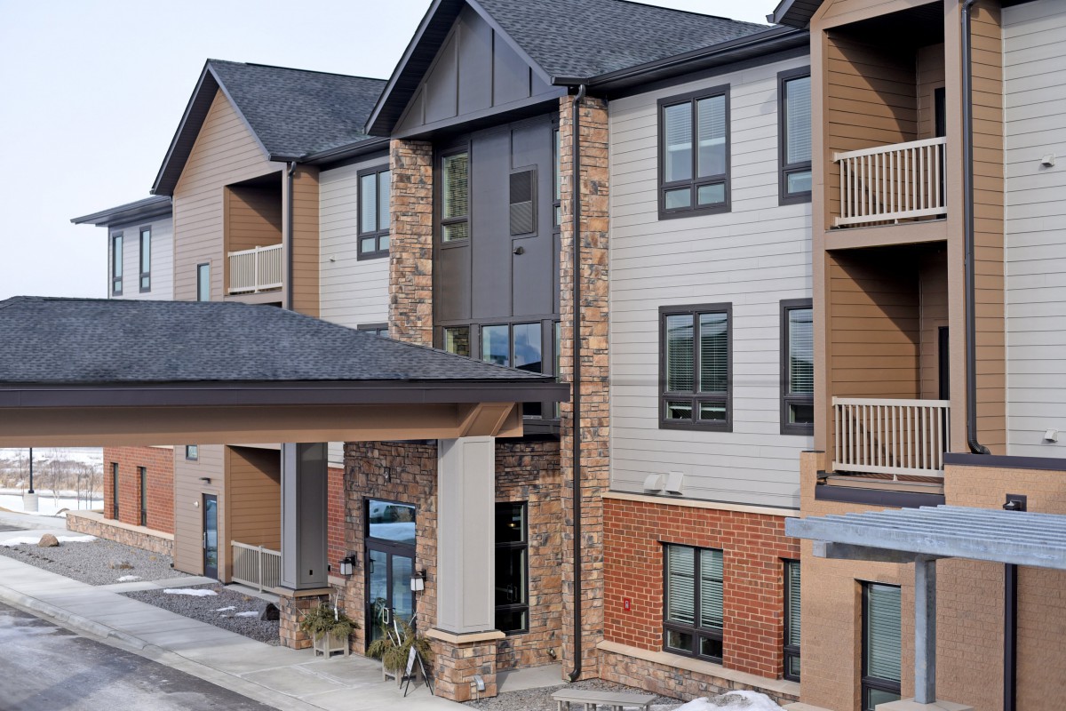 A modern residential apartment building with a mix of brick and siding materials.