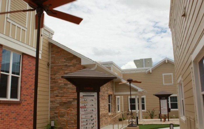 A modern building with a brick exterior and multiple rooftops against a cloudy sky.