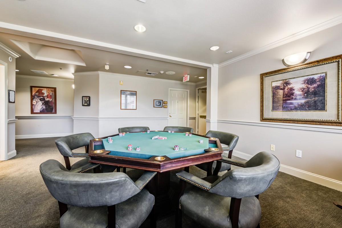 A cozy poker room featuring a classic game table and comfortable chairs.