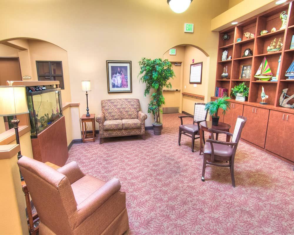 A cozy lobby area with comfortable seating, a bookshelf, and decorative plants.