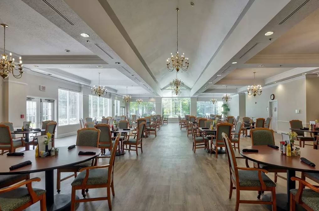 A spacious dining room with elegant chandeliers and neatly arranged tables and chairs.
