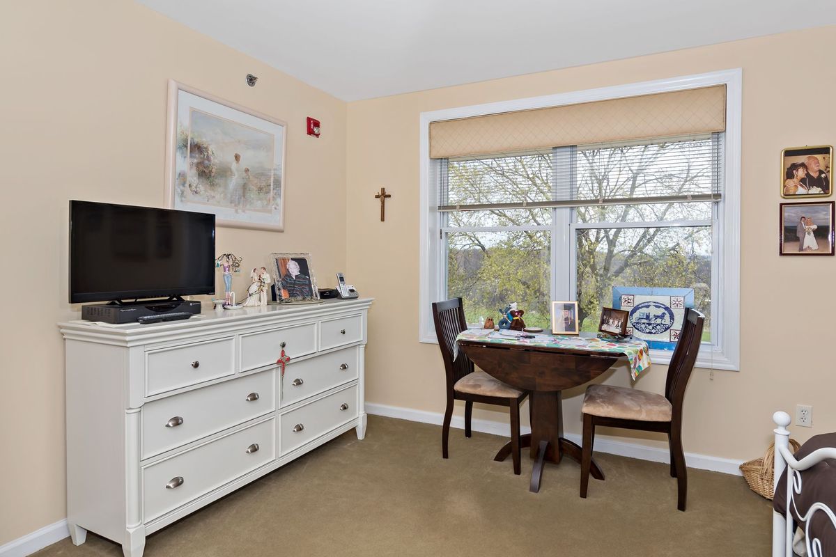 A cozy room with a dresser and a small dining table by the window.