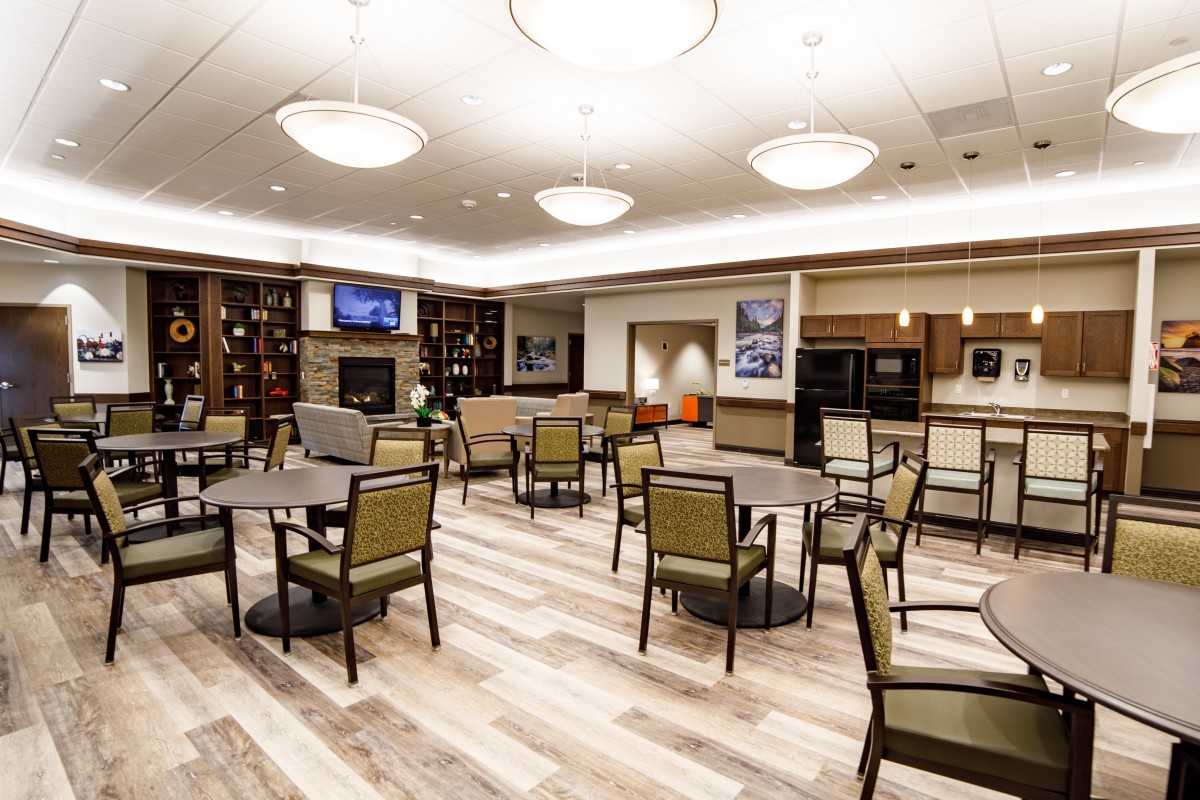 A modern dining area with neatly arranged tables and chairs, enhanced by stylish lighting and wood flooring.