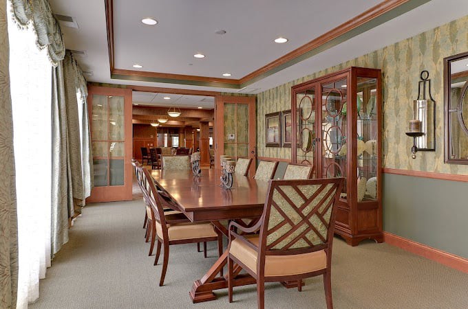 An elegant dining room with a long wooden table, upholstered chairs, and a glass-front china cabinet.