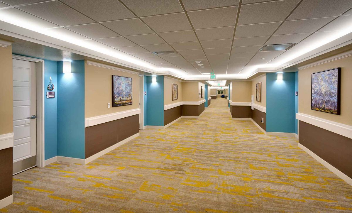 A modern hotel hallway with bright lighting and patterned carpet.