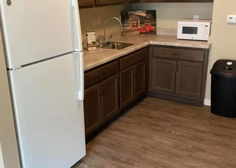 A kitchen area featuring a refrigerator, microwave, and wooden cabinets.