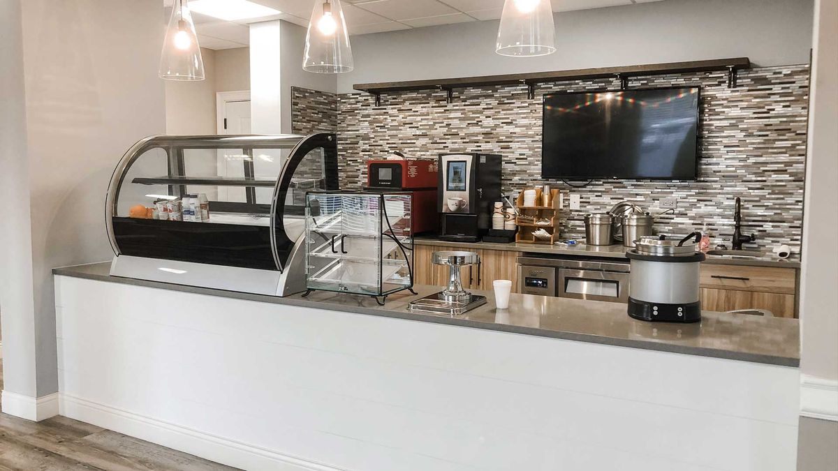 A modern cafe counter with coffee machines and a display case.