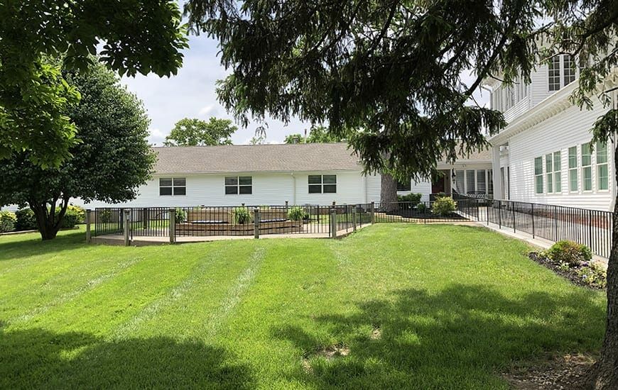 A suburban house with a large green lawn and surrounding trees.