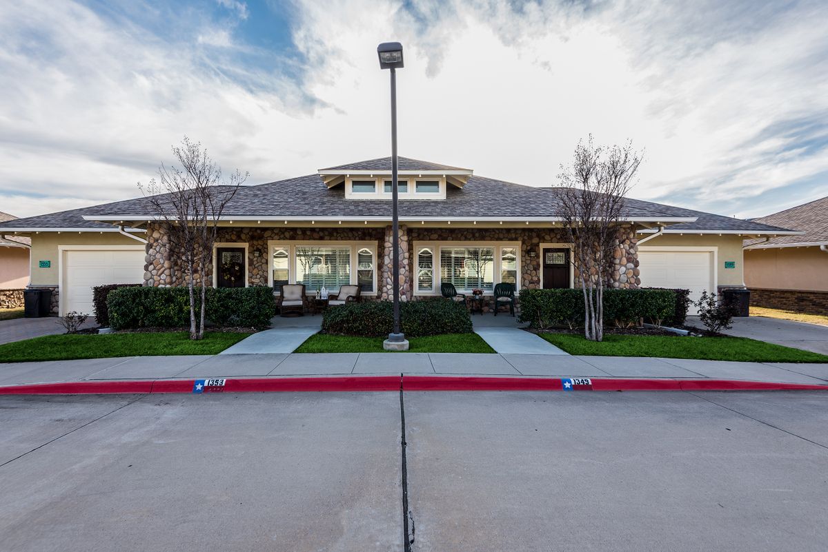 A suburban residential building with neatly landscaped front and a clear driveway.