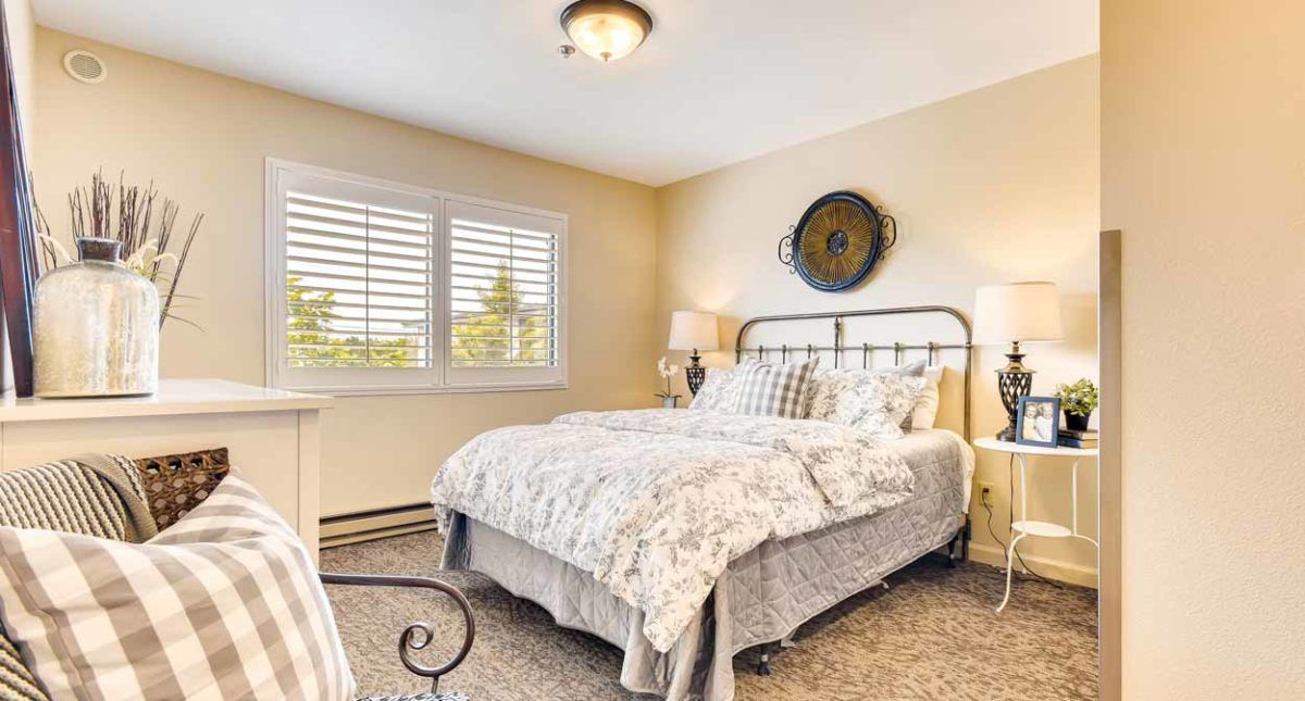 A cozy bedroom with a metal bed frame, soft bedding, and warm lighting.