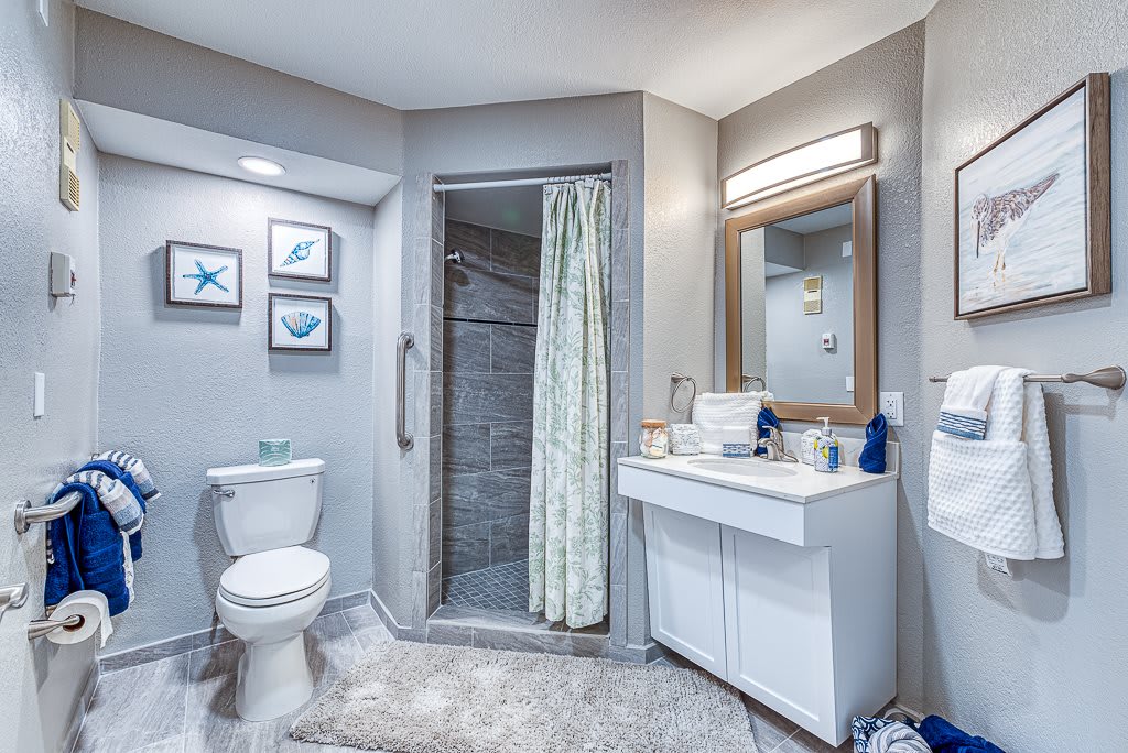 A modern bathroom with a shower, sink, and toilet, featuring clean decor and neutral colors.