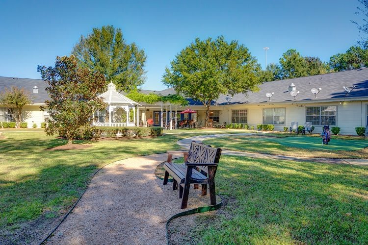 A peaceful garden with a bench and gazebo on a sunny day.