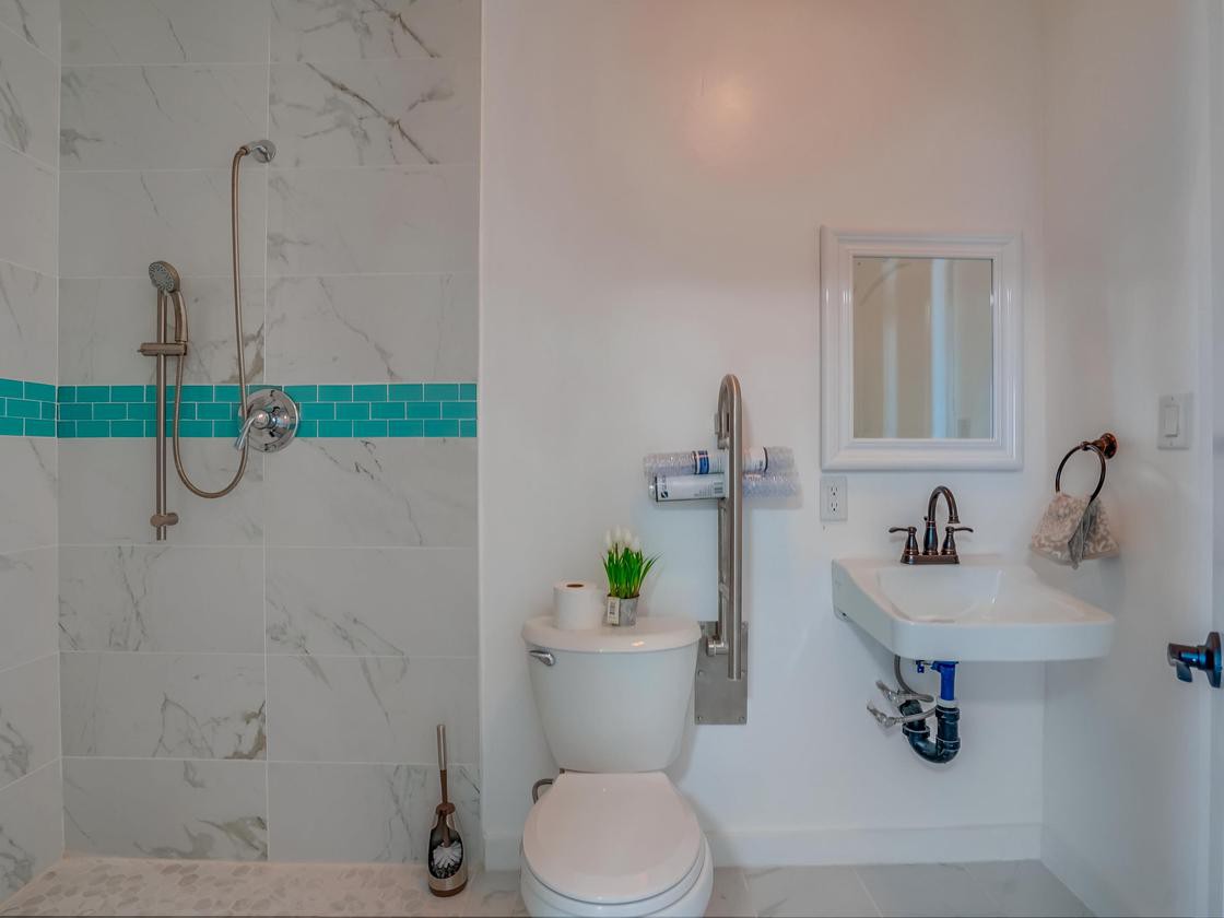 A modern, handicap-accessible bathroom with a shower, toilet, and sink.