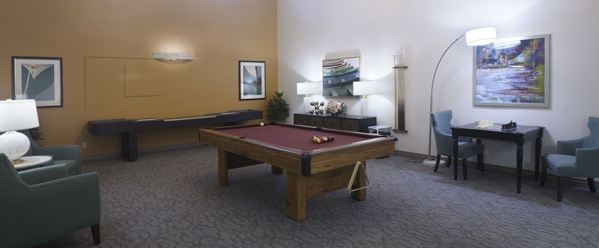 A stylish game room featuring a pool table with red felt, surrounded by modern decor and lighting.