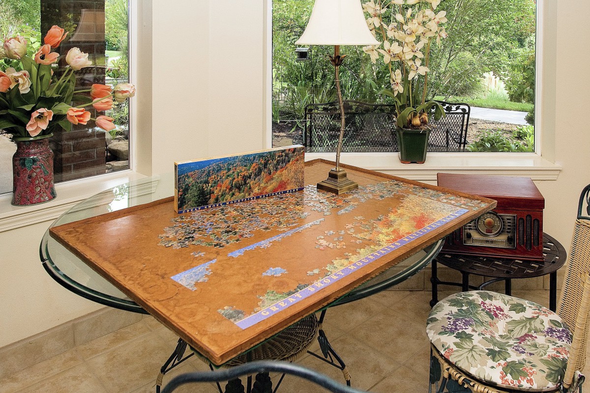 A cozy interior scene featuring a partially completed puzzle on a wooden table near a window.
