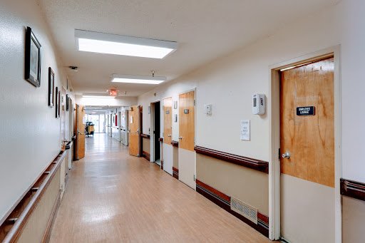 A clean and well-lit hospital hallway, lined with doors leading to different rooms.