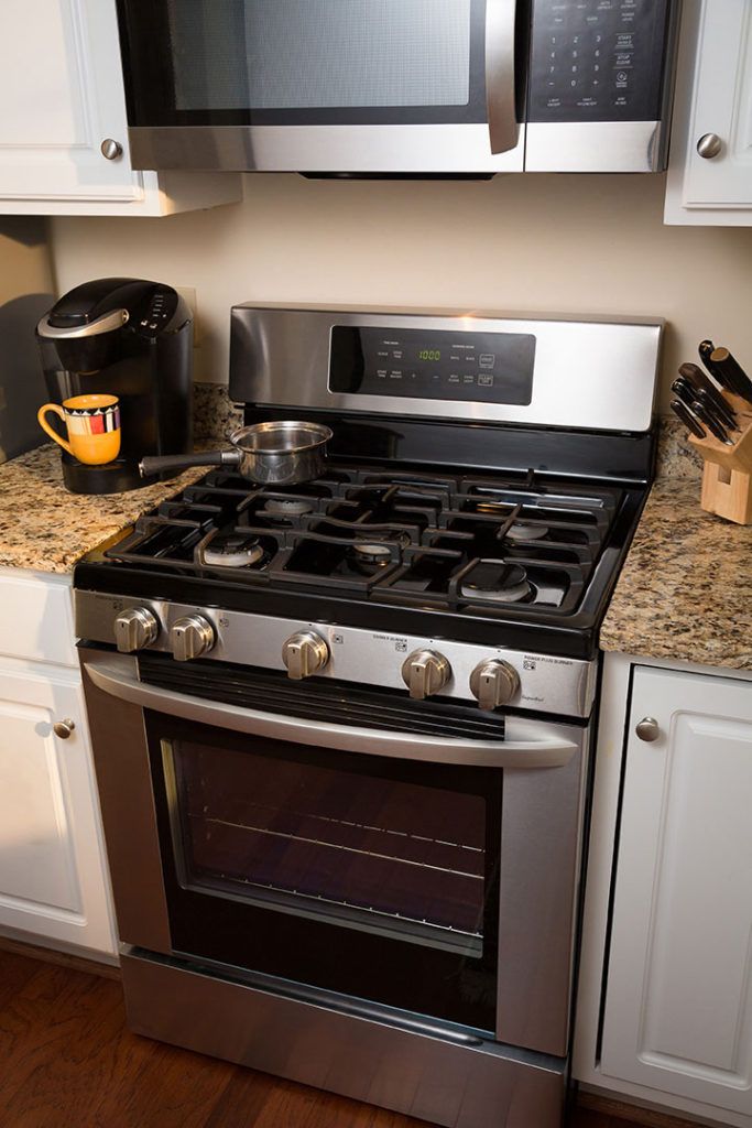 A modern kitchen with a stainless steel gas stove and oven, accompanied by a coffee maker on the countertop.