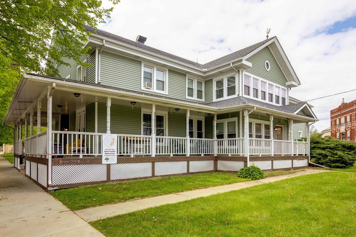 A two-story residential house with a large porch and well-kept lawn.
