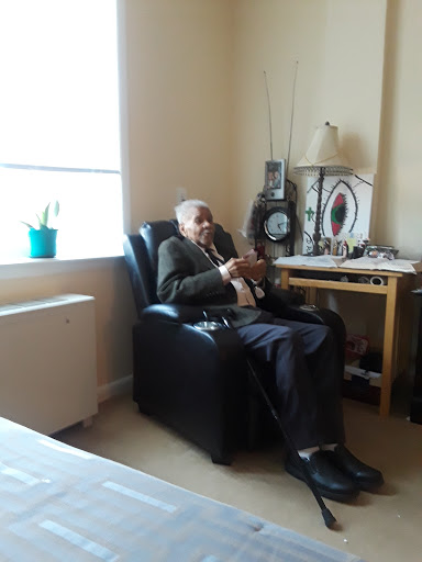 An elderly man sitting comfortably in a chair, enjoying his surroundings in a cozy living space.