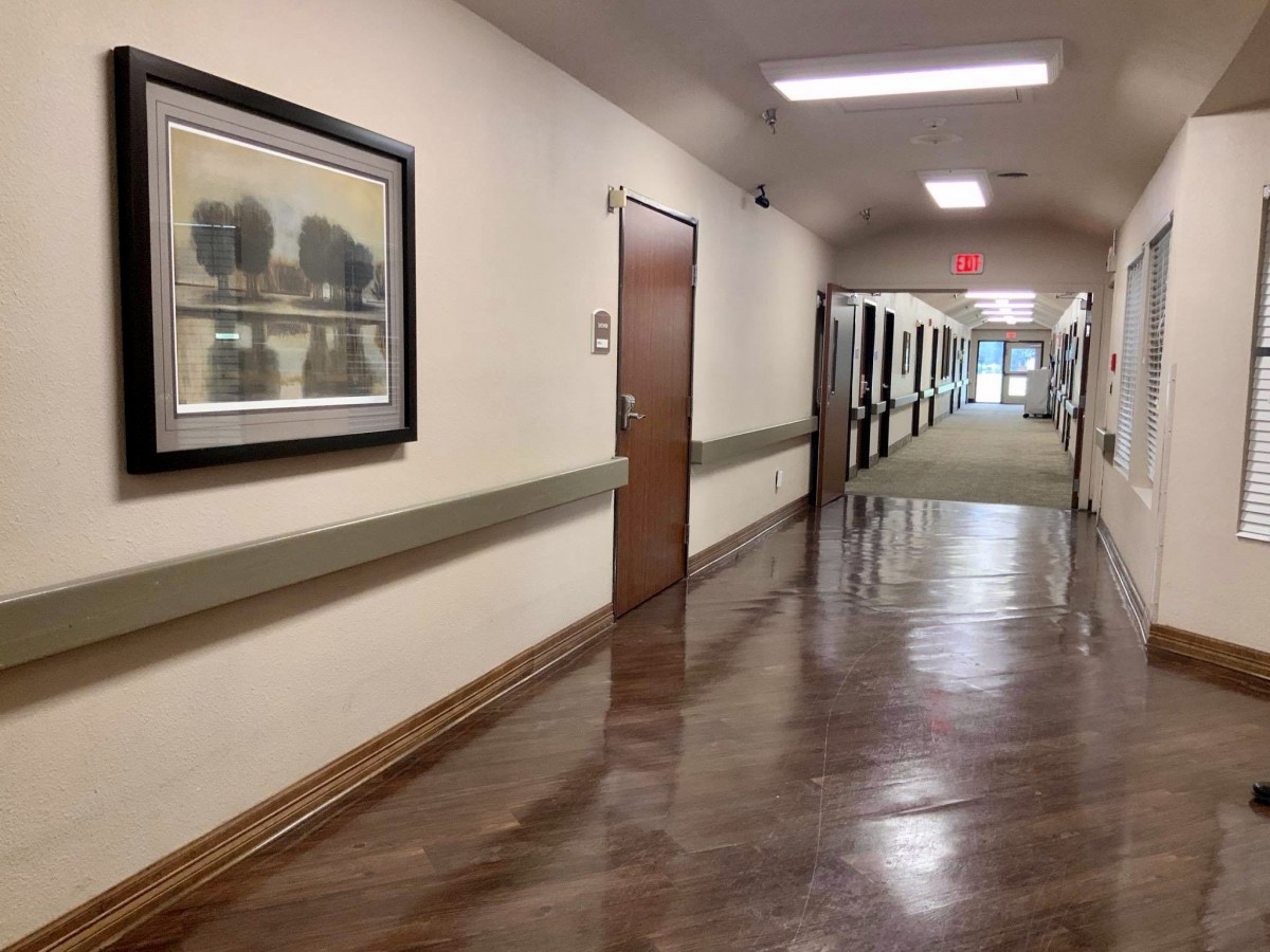 A long hallway in a hospital with shiny flooring and artwork on the walls.