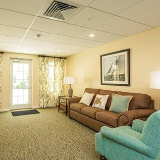 A cozy living room with a sofa, armchair, and large window adorned with curtains.
