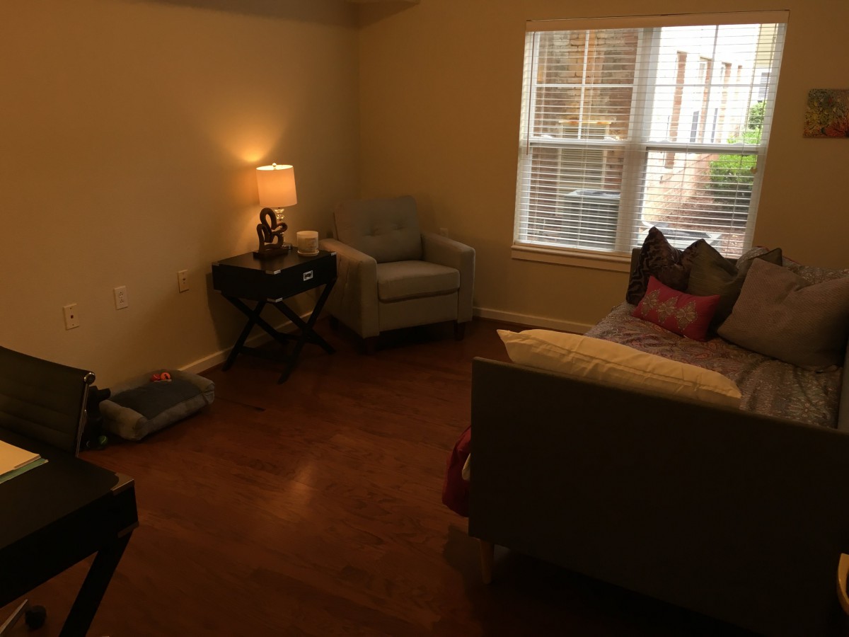 A cozy living room with a sofa, armchair, and a side table with a lamp.