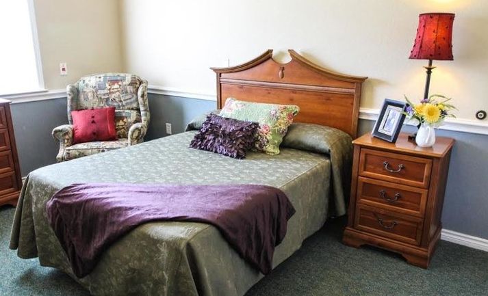 A cozy bedroom with a neatly made bed, wooden headboard, and nightstand.