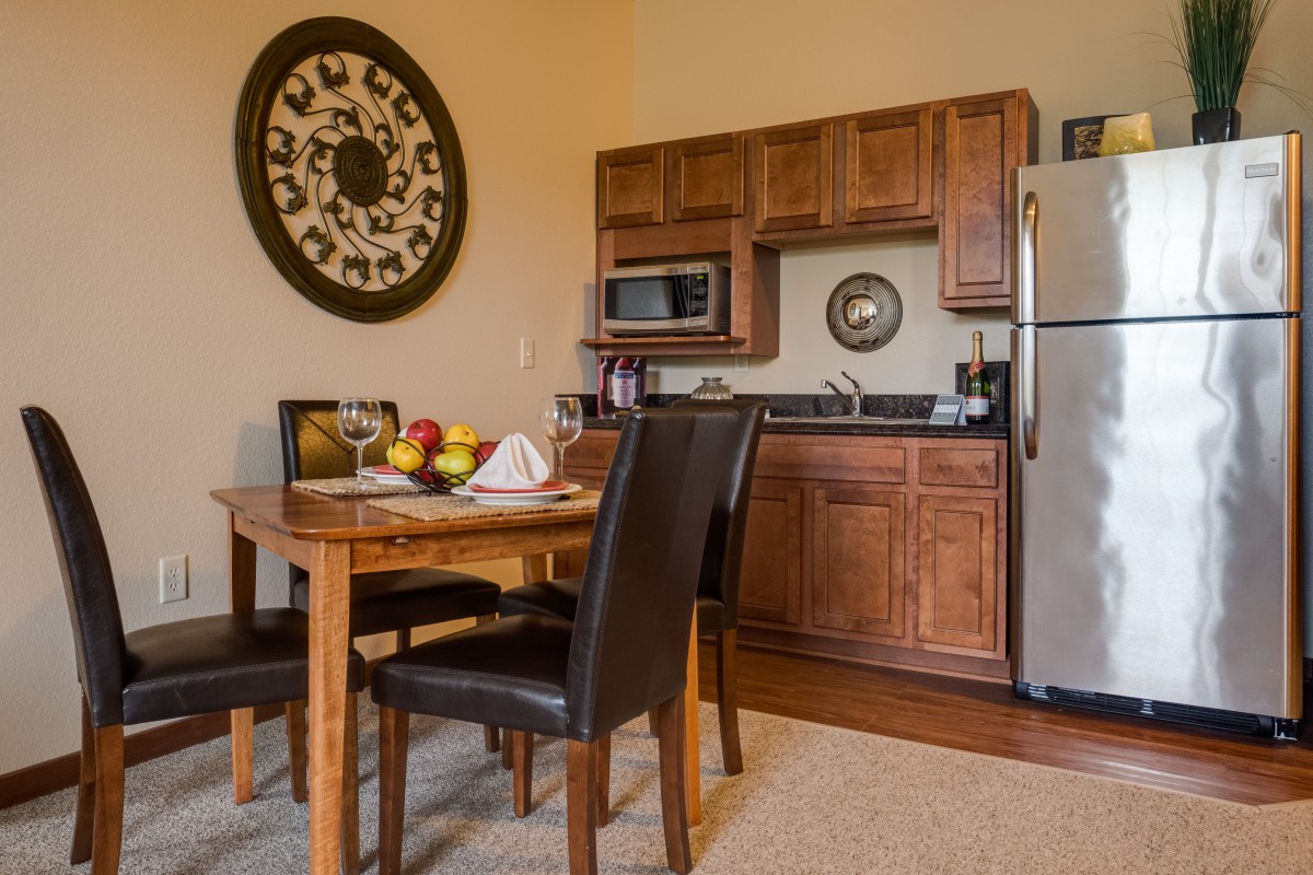 A cozy kitchen and dining area featuring wood cabinets and a dining table with leather chairs.