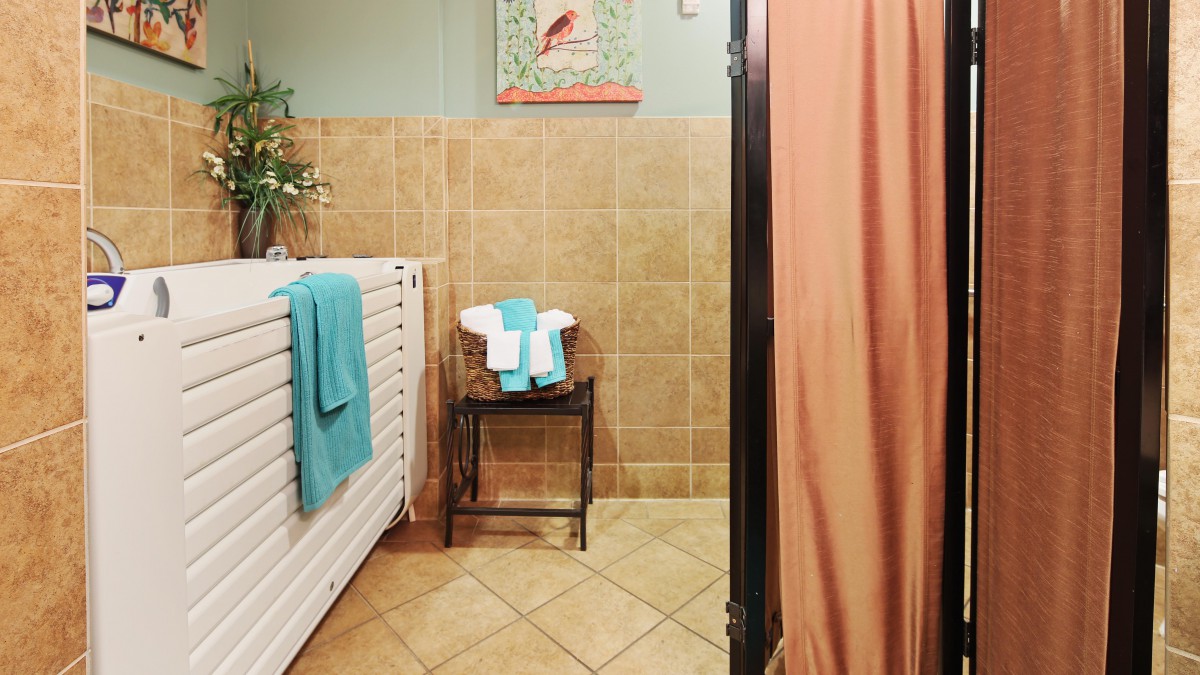 A cozy bathroom with stacked towels, a radiator, and a tiled shower.