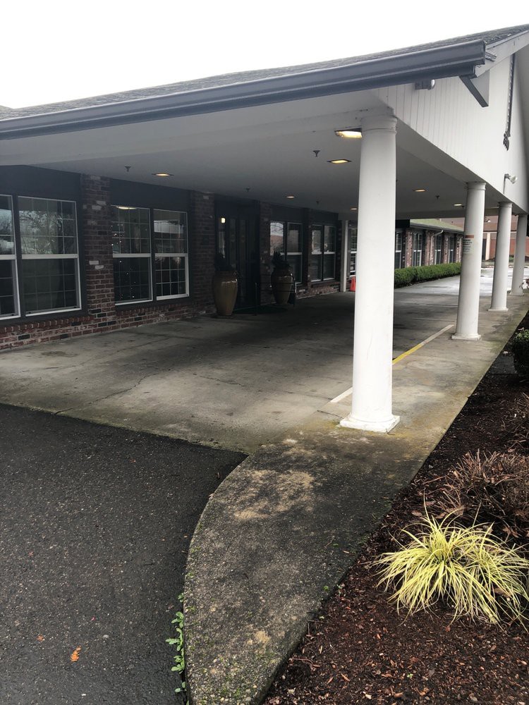 A covered building entrance with white columns and landscaping.