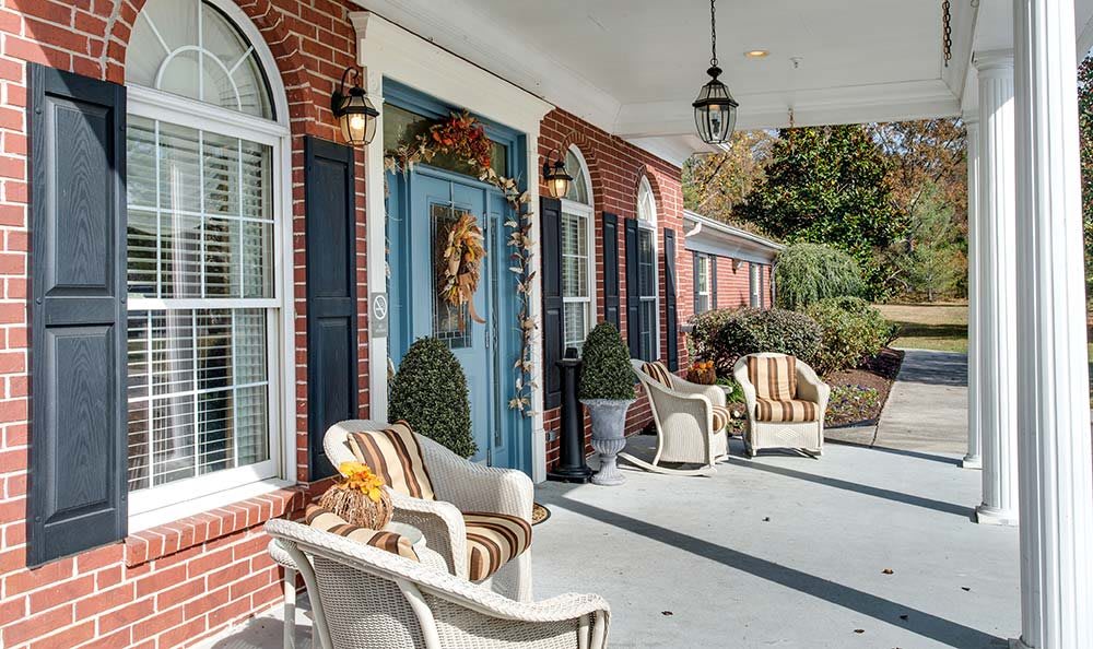 A cozy front porch with wicker chairs and a decorated blue door.