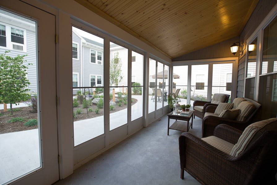 A cozy sunroom with large windows overlooking a garden patio.